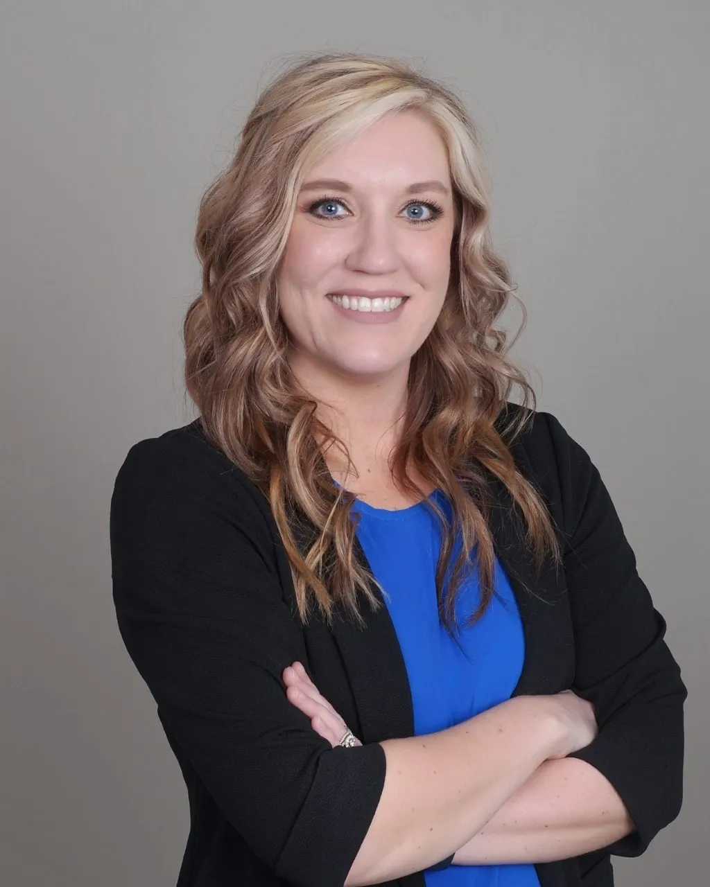 A woman with long hair and a blue shirt is smiling.